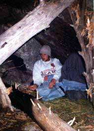 Camping between two boulders with wood and grass cover.