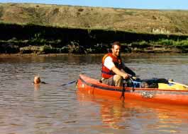 Canoe towing a kid swimming.